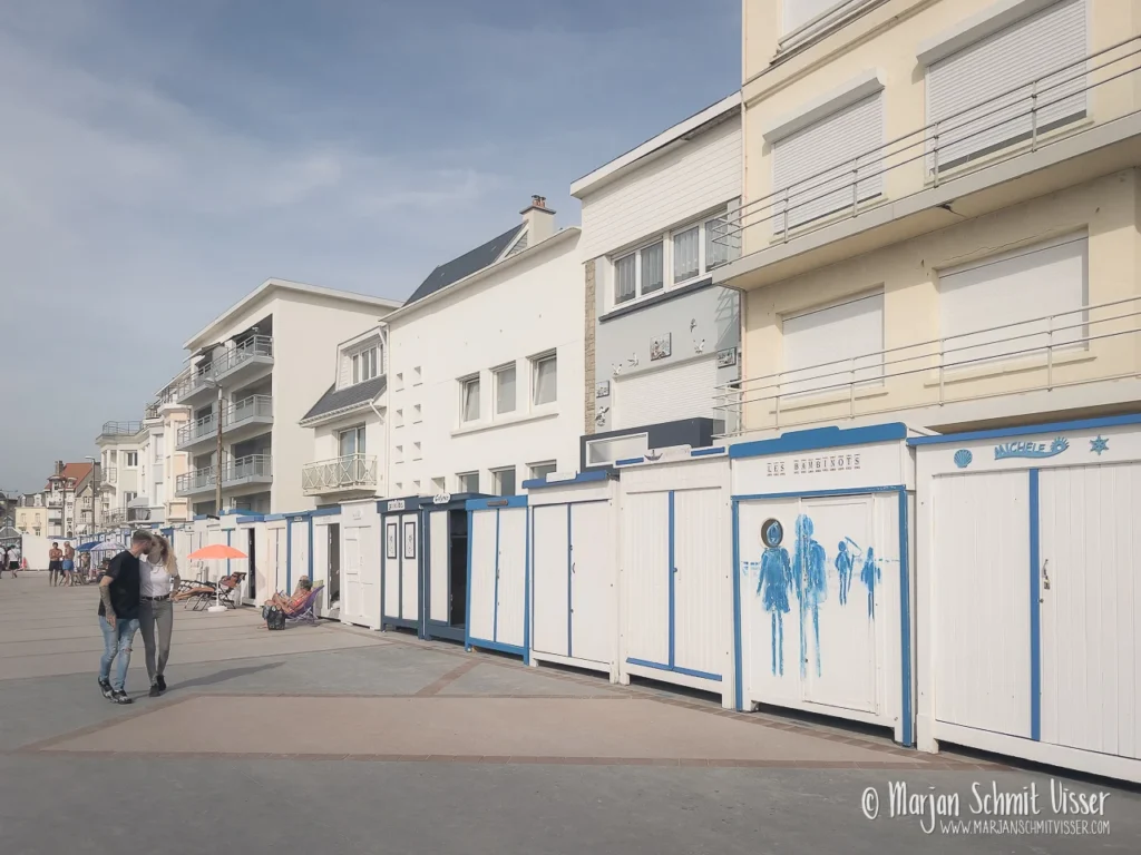 Boulevard van Wimereux met witte strandhuisjes, lichte appartementsgebouwen en wandelaars op een zonnige dag.